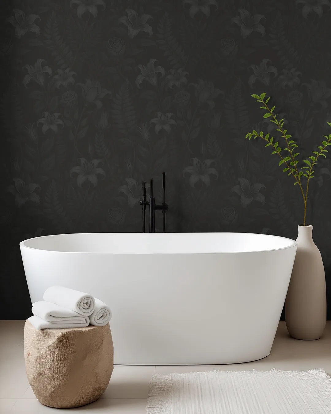 Modern bathroom with a white freestanding bathtub, towels on a stone stool, and a vase with greenery against a dark floral-patterned wallpaper by Buffalo Bunny..