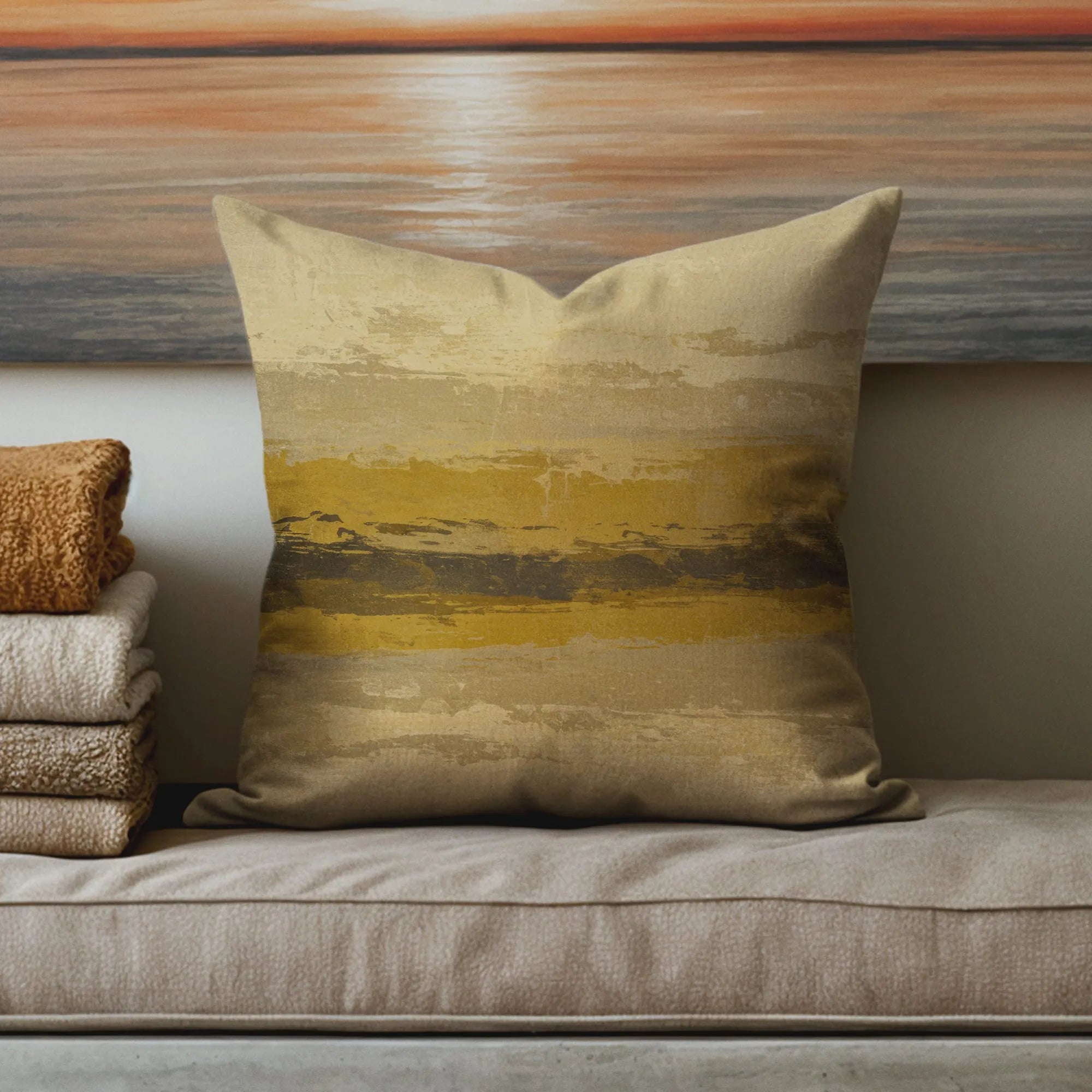Beige throw pillow with abstract horizontal brushstroke design in mustard yellow and dark brown tones on cushioned bench.