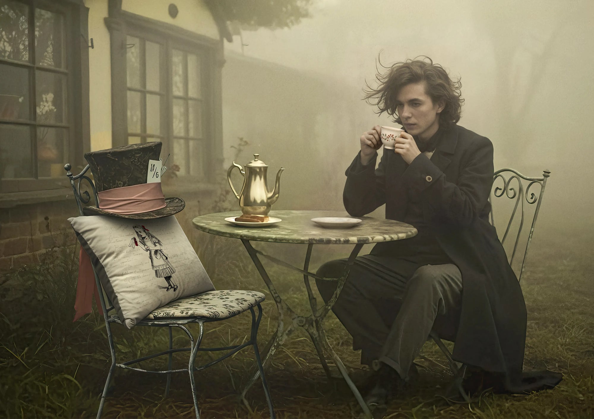 Man sitting at a table outdoors in a foggy setting with a vintage teapot and cup.