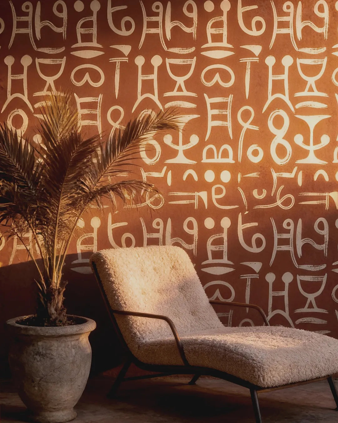 Decorative chair and potted plant against a wall featuring the Ancient Script Wallpaper