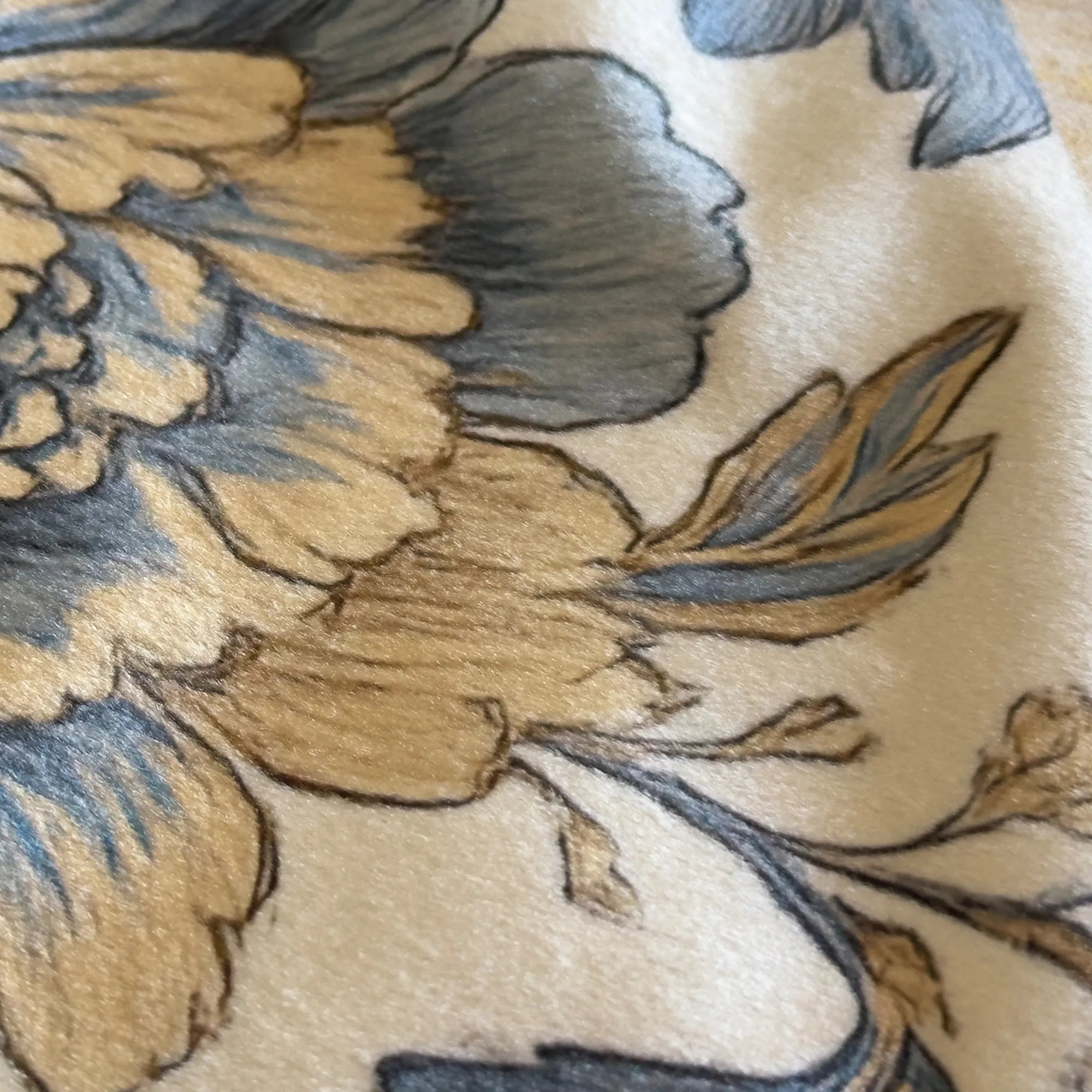 Close-up of floral embroidery on fabric with blue and brown colors.