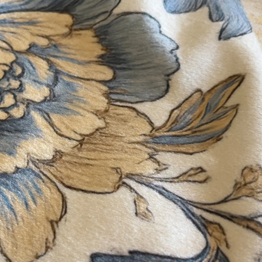 Close-up of floral embroidery on fabric with blue and brown colors.