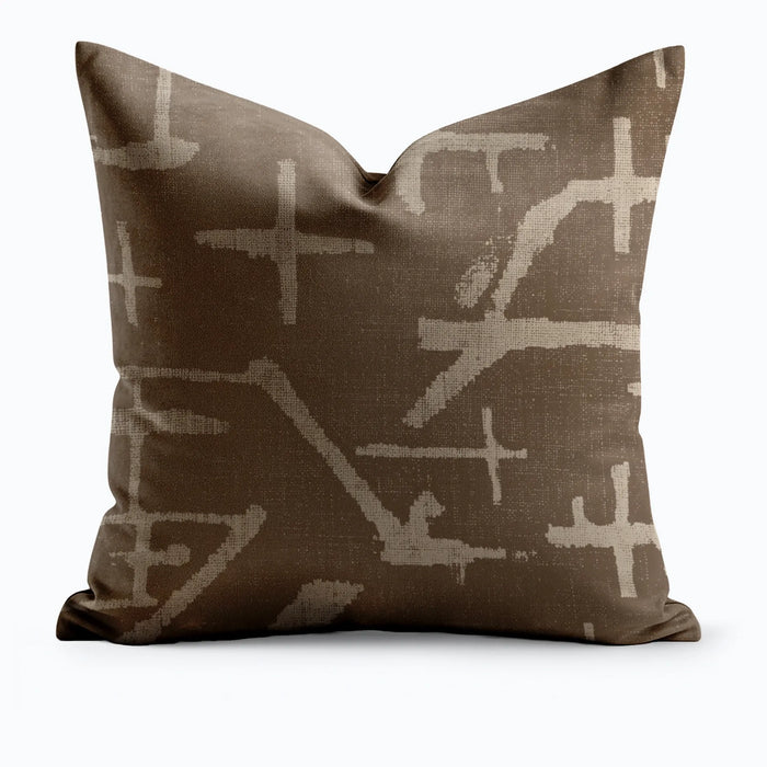 Desert Mark throw pillow with large-scale abstract cross and line marks in sand on dark chocolate brown