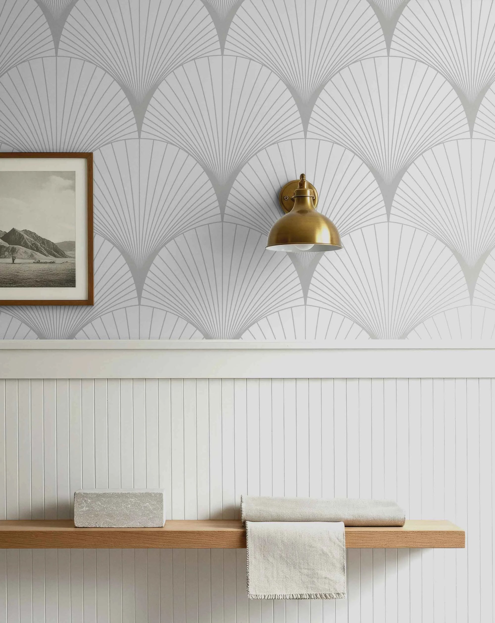 Decorative wall with geometric light gray pattern. Gold sconce, a picture frame and and wooden shelf.
