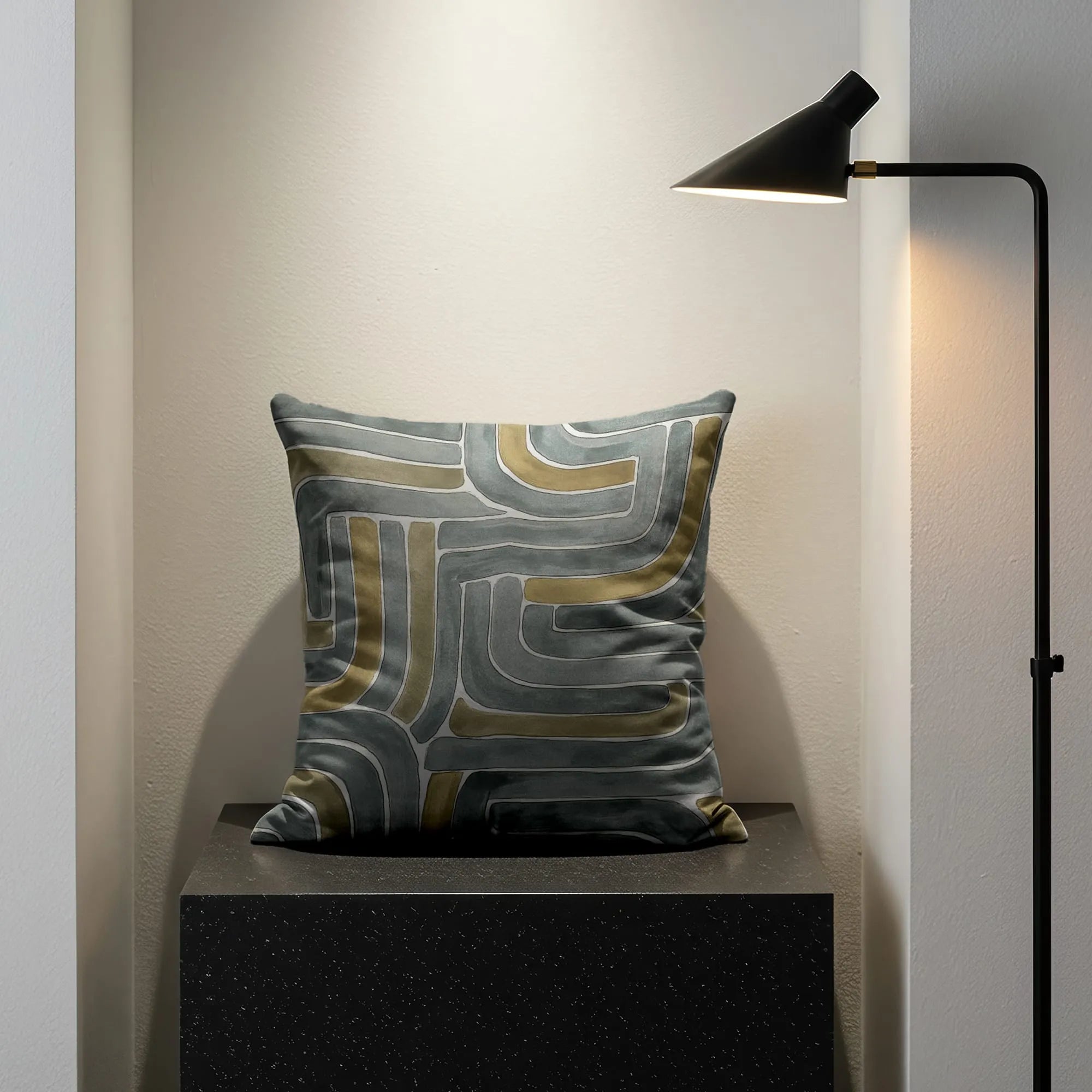 Geometric abstract Buffalo Bunny pillow in grey, olive, and cream tones on black granite plinth in minimalist gallery nook