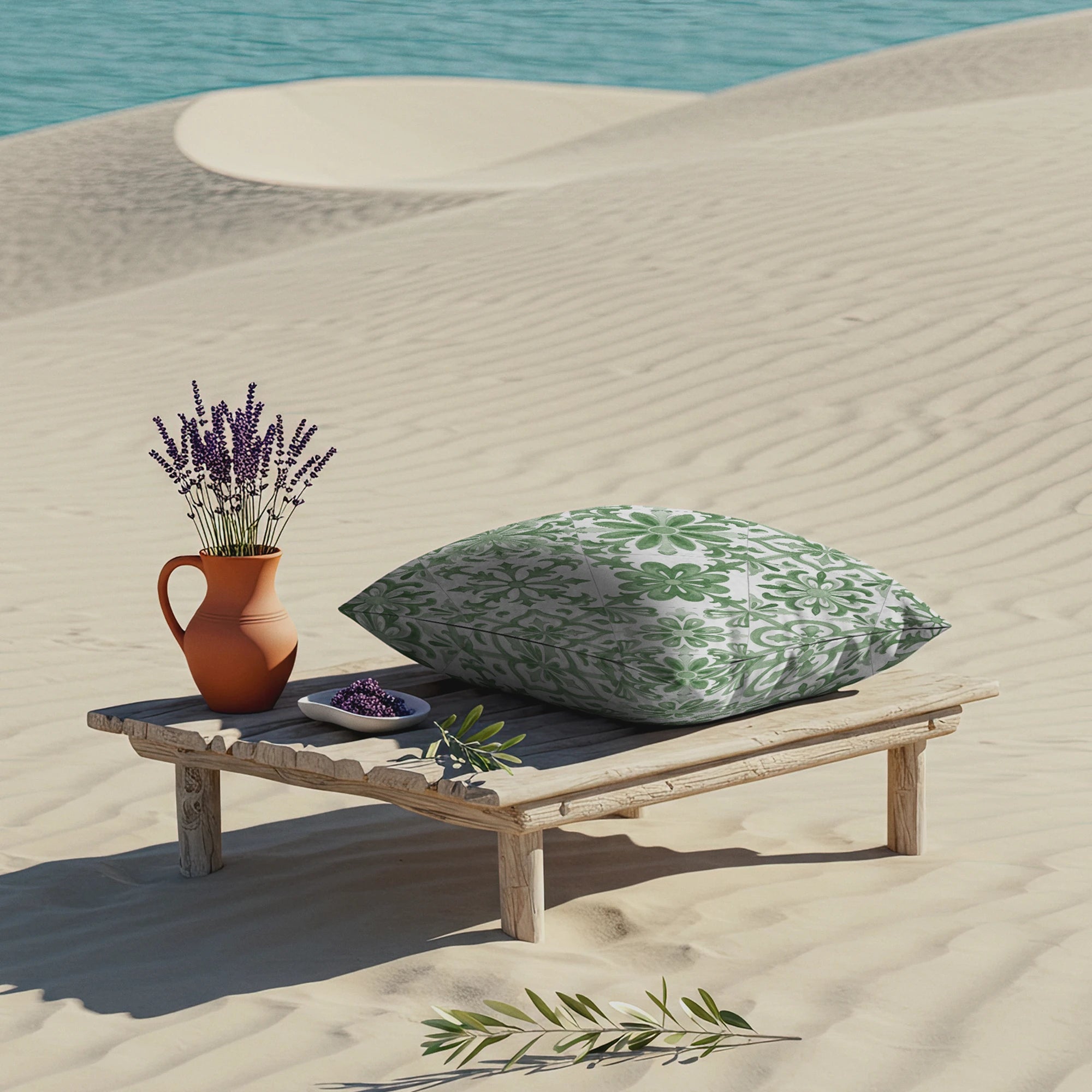 Serene desert beach scene with vintage tile-print pillow on a rustic wooden platform, accompanied by a terracotta vase of lavender, against a tranquil turquoise water background.