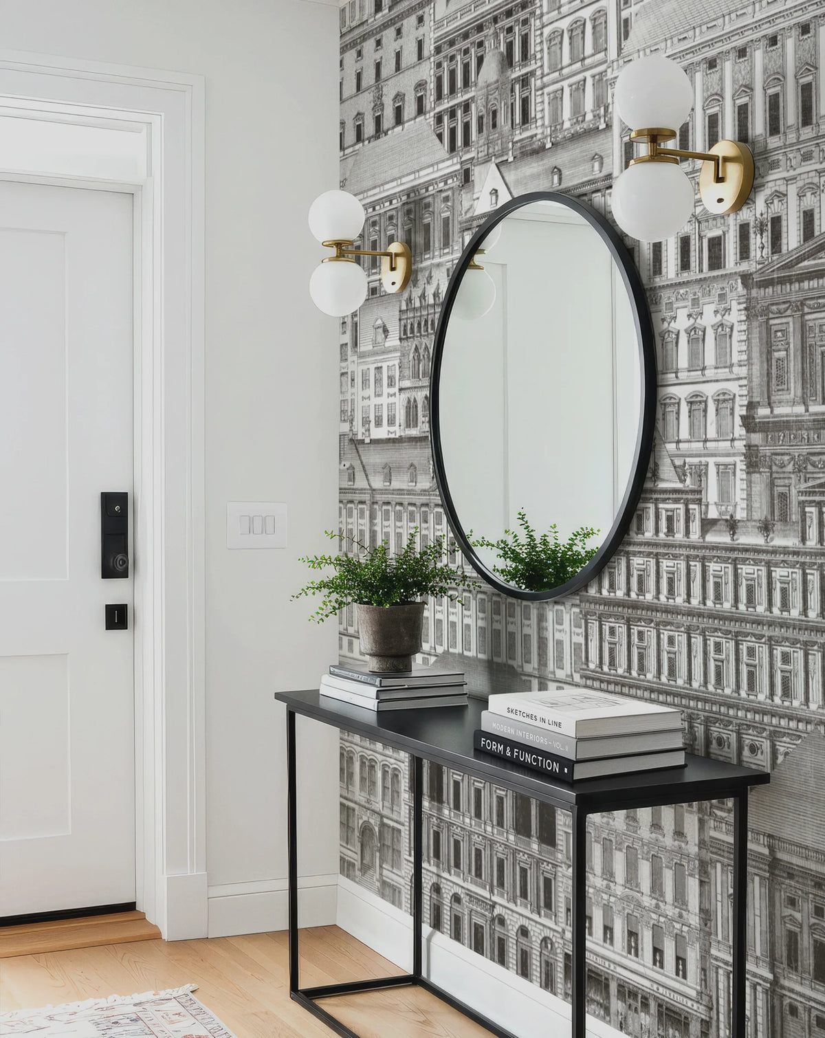 Console table with mirror and decor against a patterned wallpaper city mural by Buffalo Bunny.