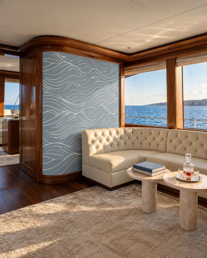 Quiet Current Mural Wallpaper with flowing white wave lines on soft blue, framed by warm walnut paneling beside a cream tufte
